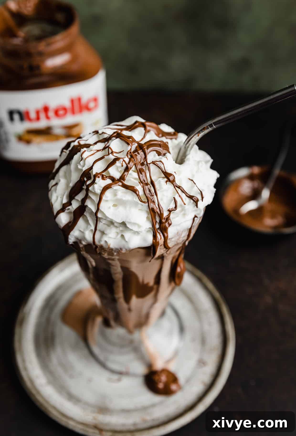 Overhead shot of a rich Nutella shake in a clear glass cup, beautifully crowned with fluffy whipped topping, making it an irresistible dessert.