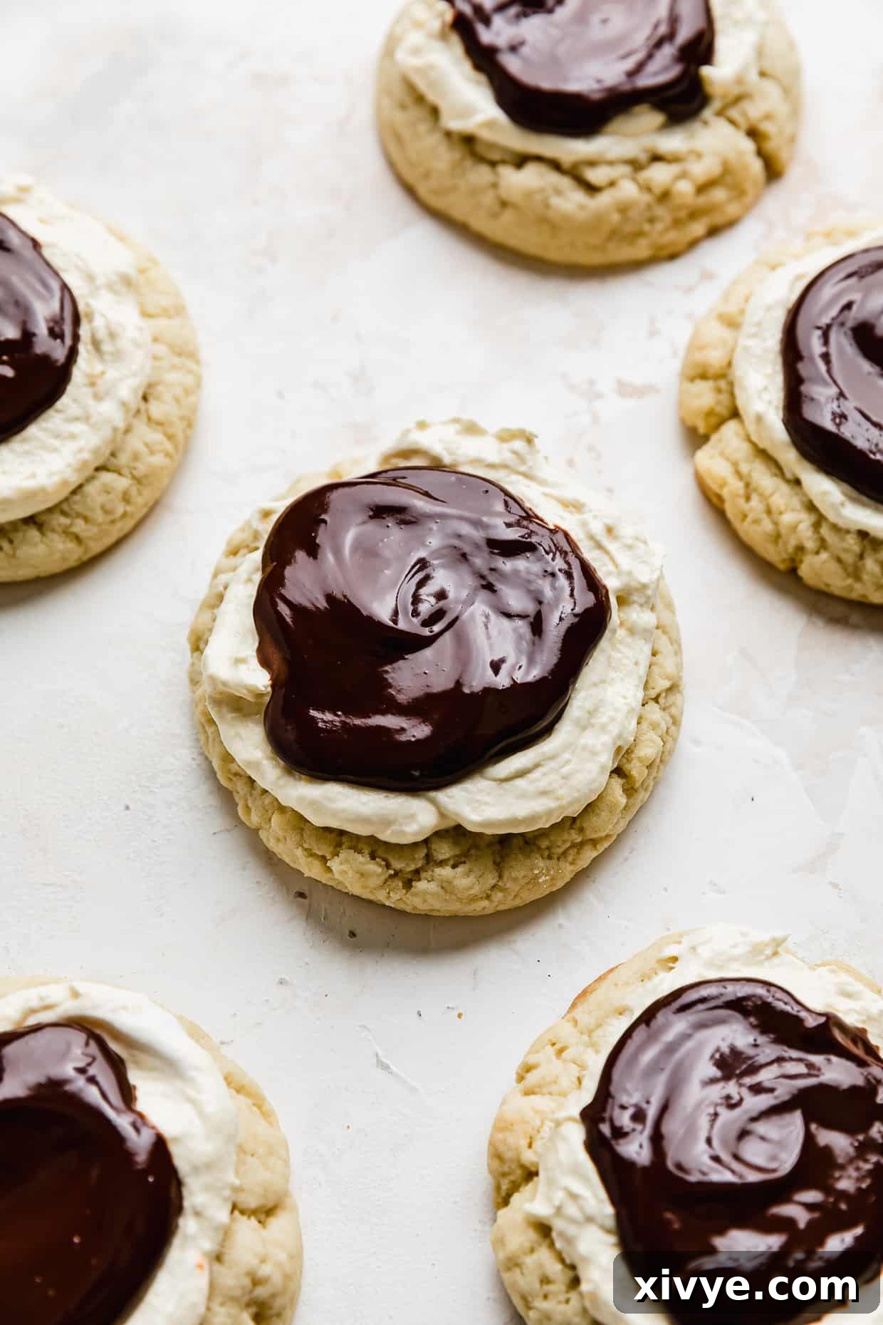 Finished Crumbl Boston Cream Pie Cookies topped with pastry cream and melted chocolate ganache, on a white background.