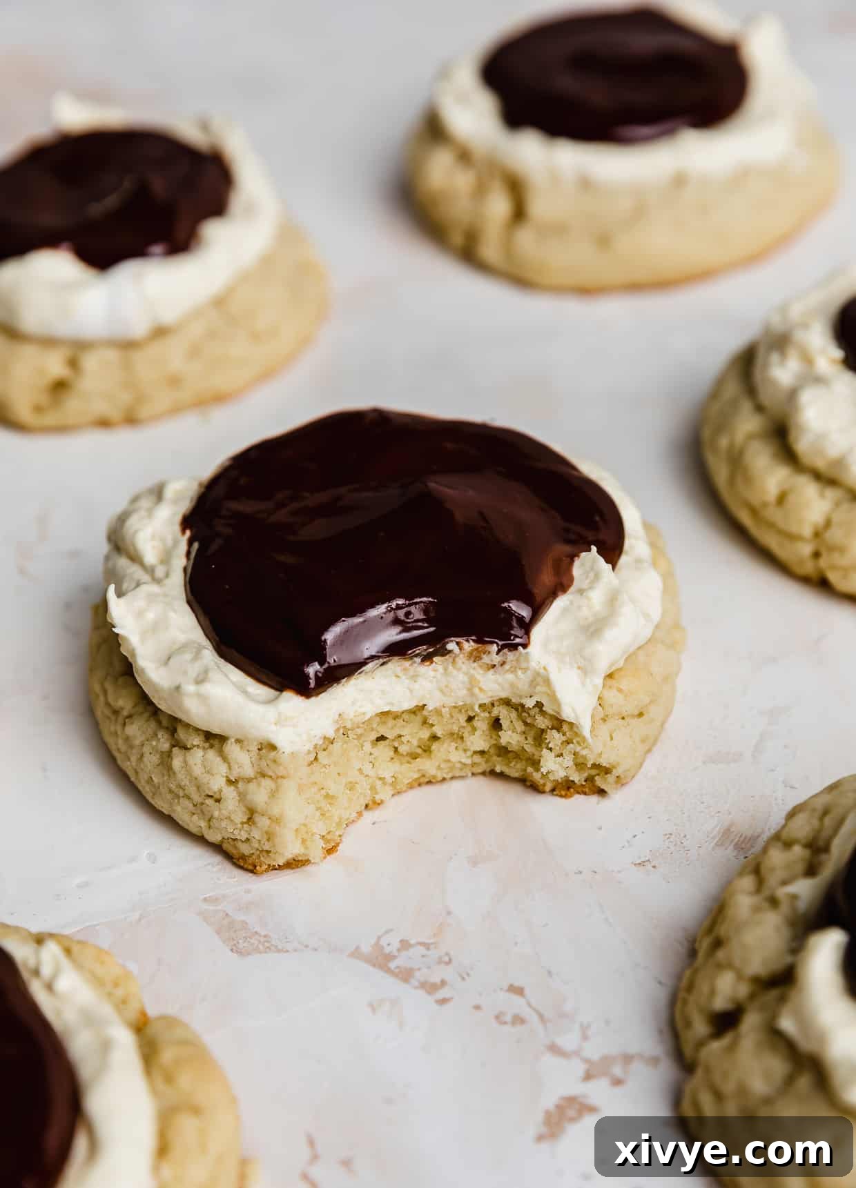 A delicious Boston Cream Pie Cookie with a bite taken out of it, showing the layers.