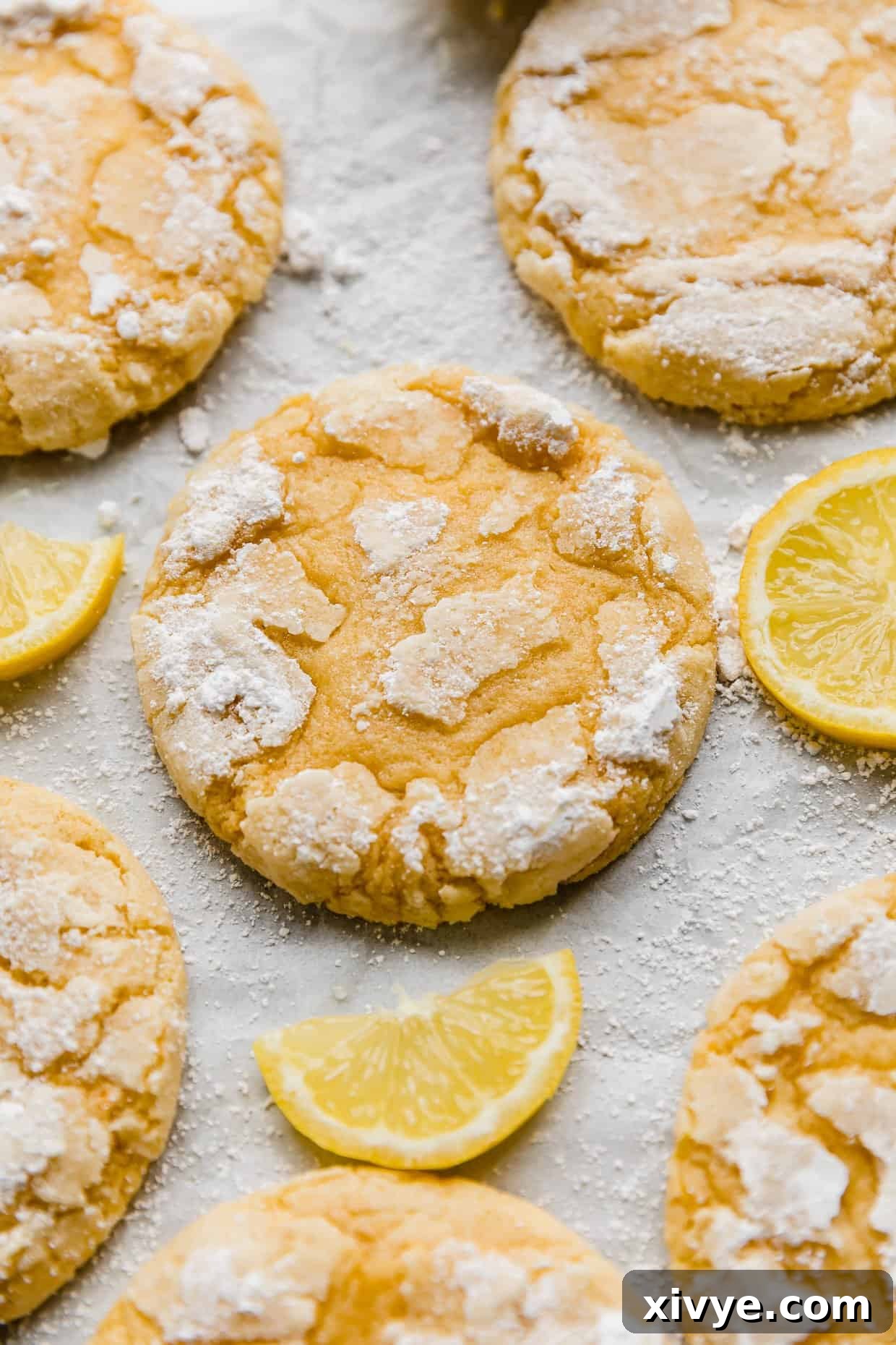 Zesty Lemon Crinkles 2 Crumbl Lemon Crinkle Cookies topped with powdered sugar on a white background, showcasing their beautiful crinkled texture.