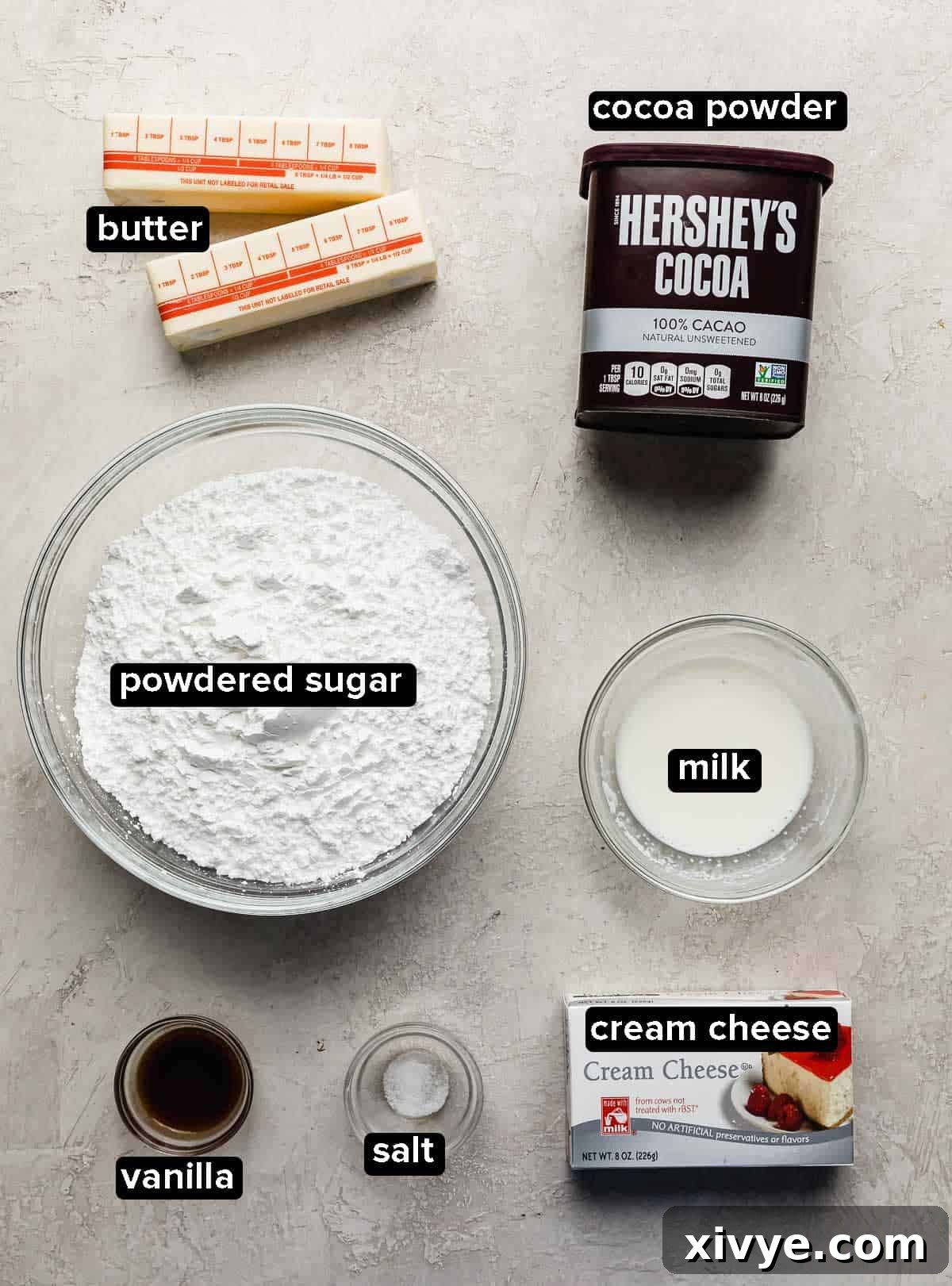 Chocolate Cream Cheese Frosting ingredients laid out on a light gray background, including softened butter and cream cheese.