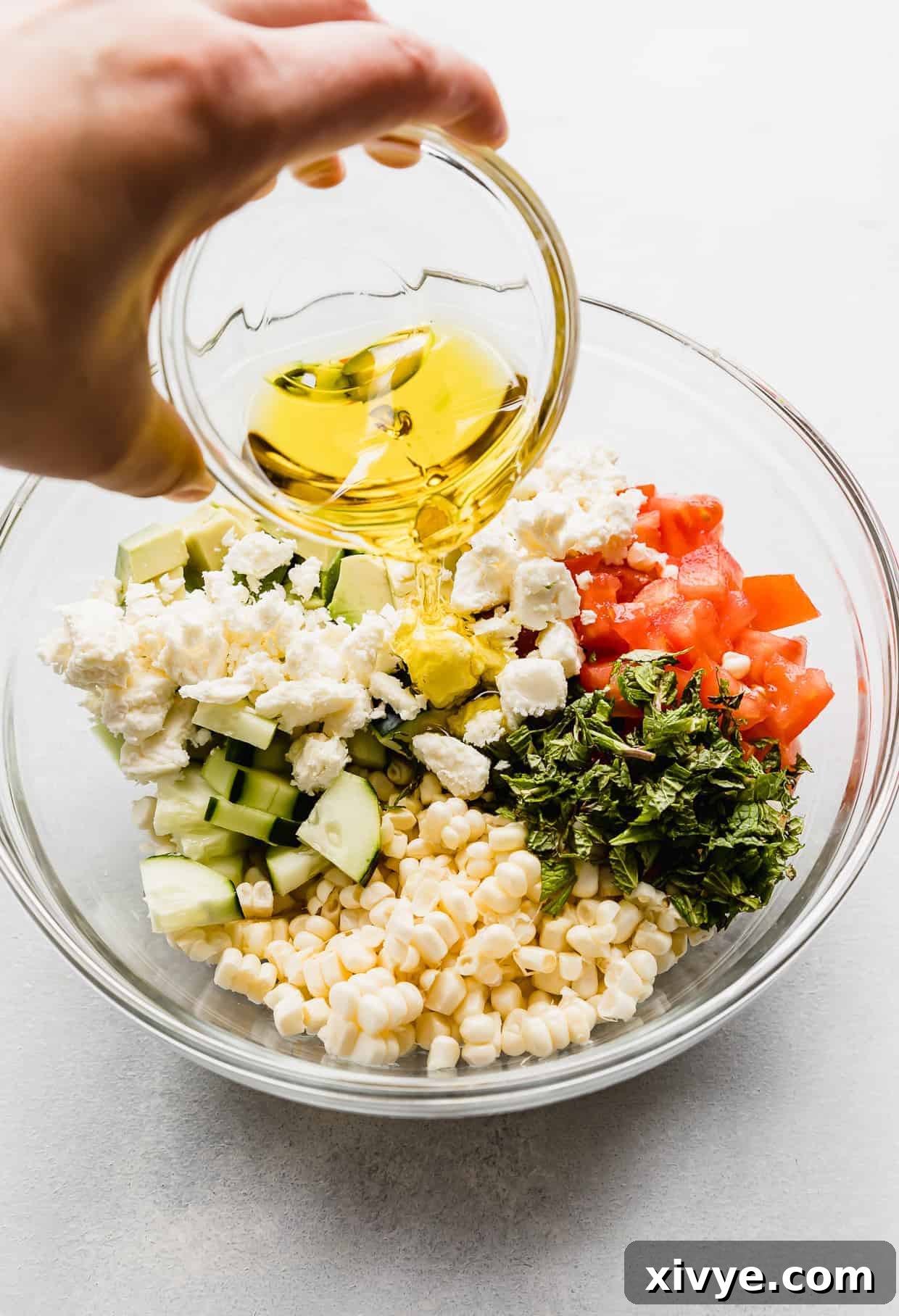 Olive oil being poured overtop of Feta Corn Salad.