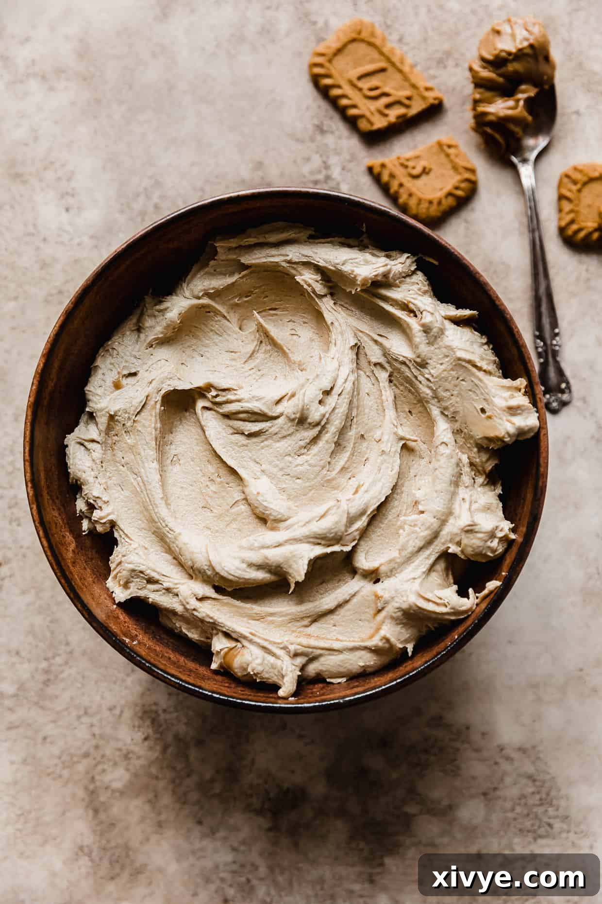 Biscoff Buttercream in a brown bowl on a light tan textured background.