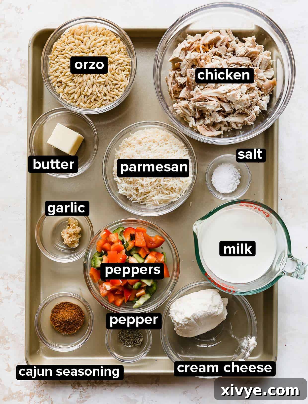 Cajun-Spiced Chicken Orzo 3 Cajun Chicken Orzo ingredients portioned into glass bowls on a baking sheet.