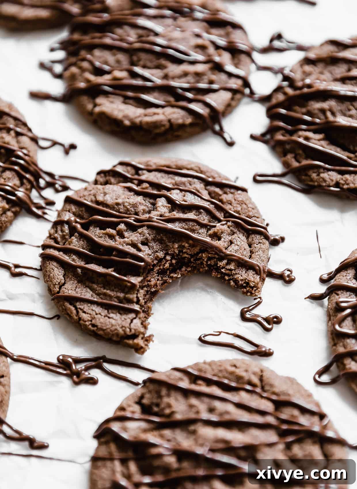 Nutella Cookies drizzled with Nutella and a bite taken out of it, showing the soft interior.