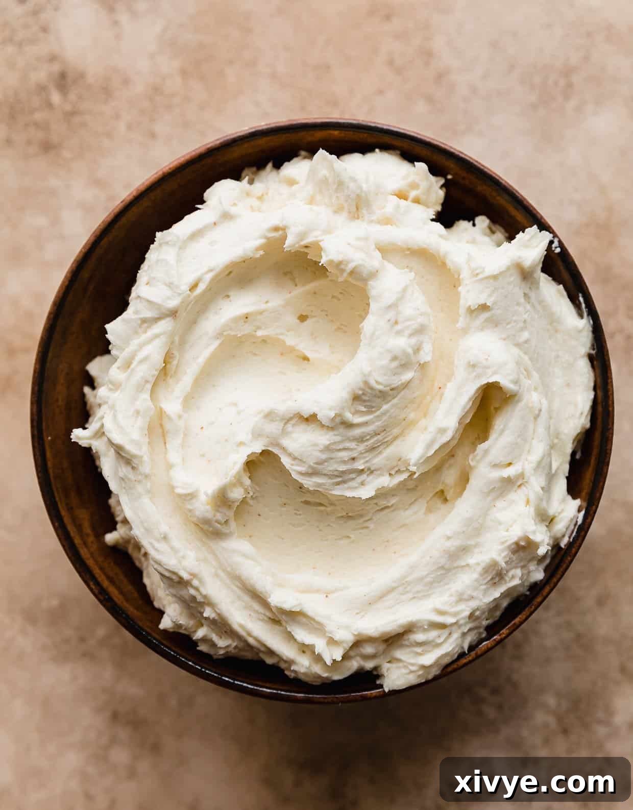 A brown bowl filled with light yellow colored Brown Butter Buttercream.