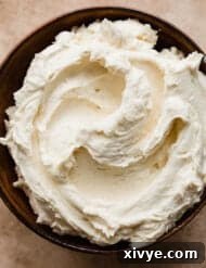 Brown Butter Buttercream in a brown bowl on a tax textured background.