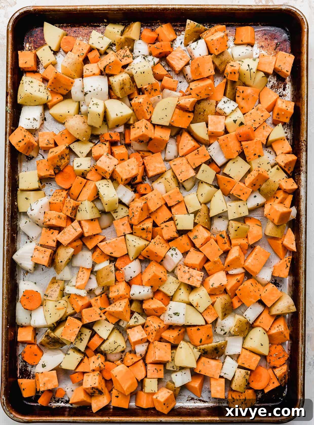 Root vegetables cut into uniform chunks, beautifully arranged on a baking sheet, ready for seasoning and roasting.