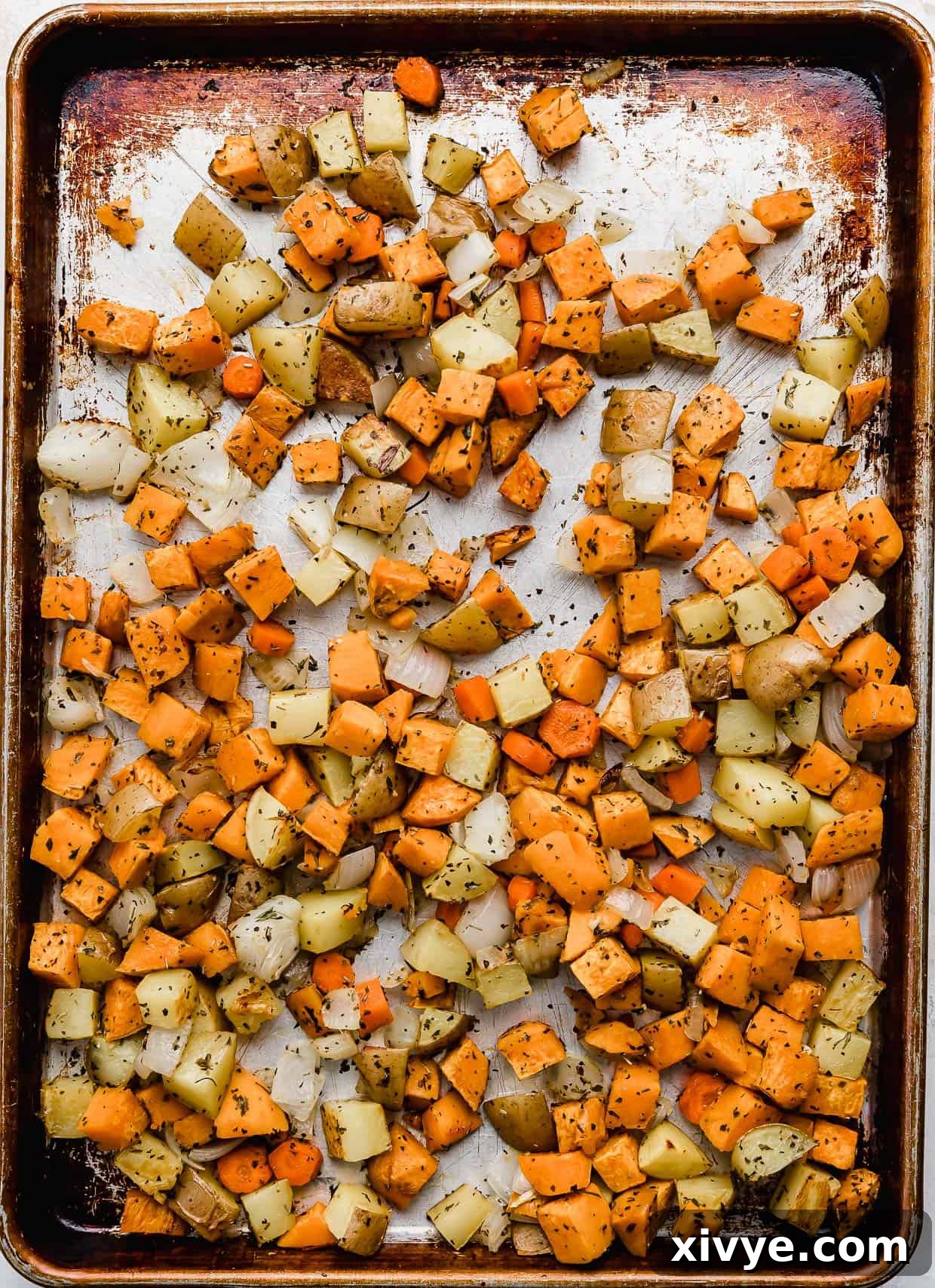 Roasted root vegetables, golden brown and tender, spread across a baking sheet after being cooked to perfection.