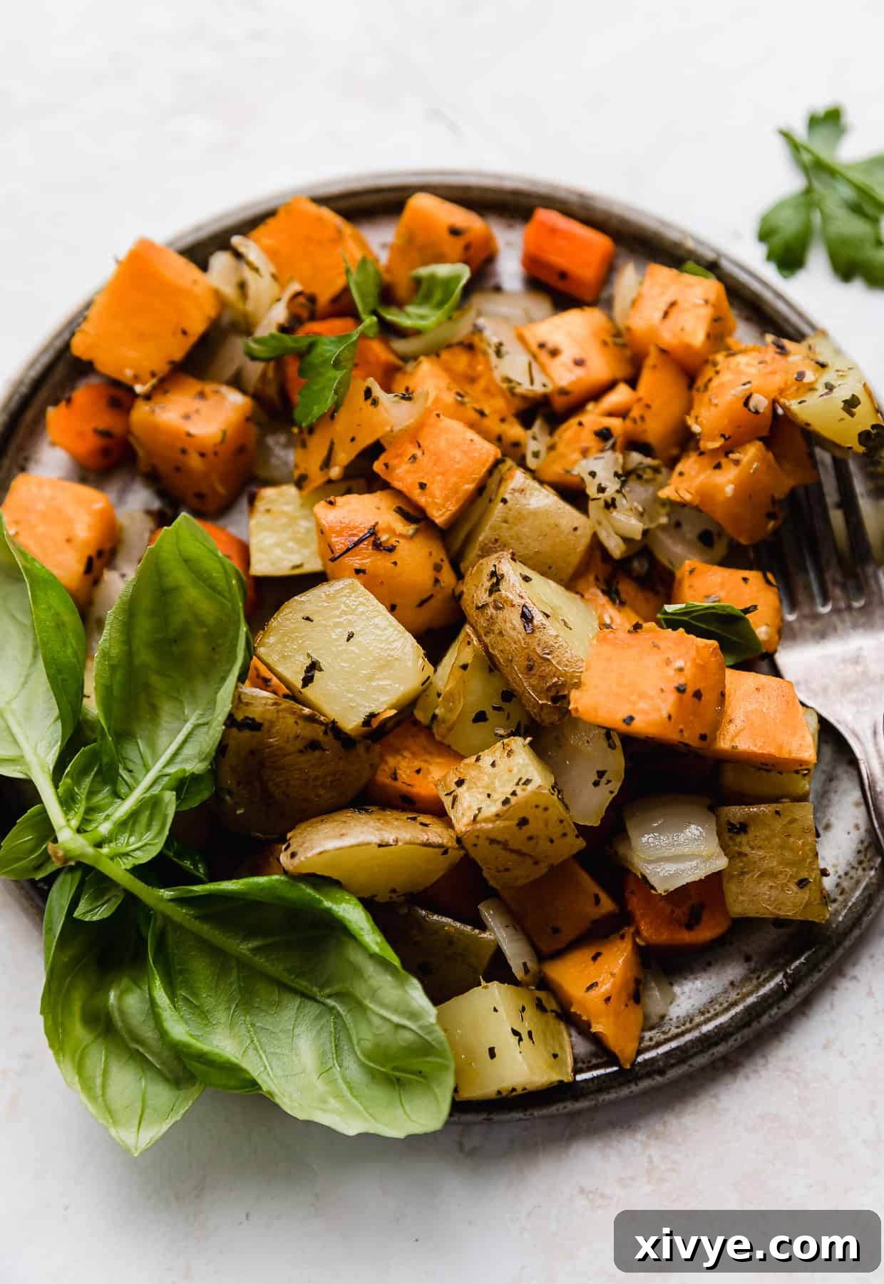A close-up photo of chopped roasted root vegetables on a plate, garnished with fresh herbs, showcasing their appealing golden-brown color and tender texture.