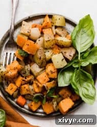 A gray plate on a white background with easy Sheet Pan Roasted Root Vegetables topped with herbs on it.