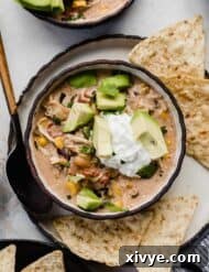 Sour cream and avocado on top of a bowl filled with cream cheese chicken chili recipe.