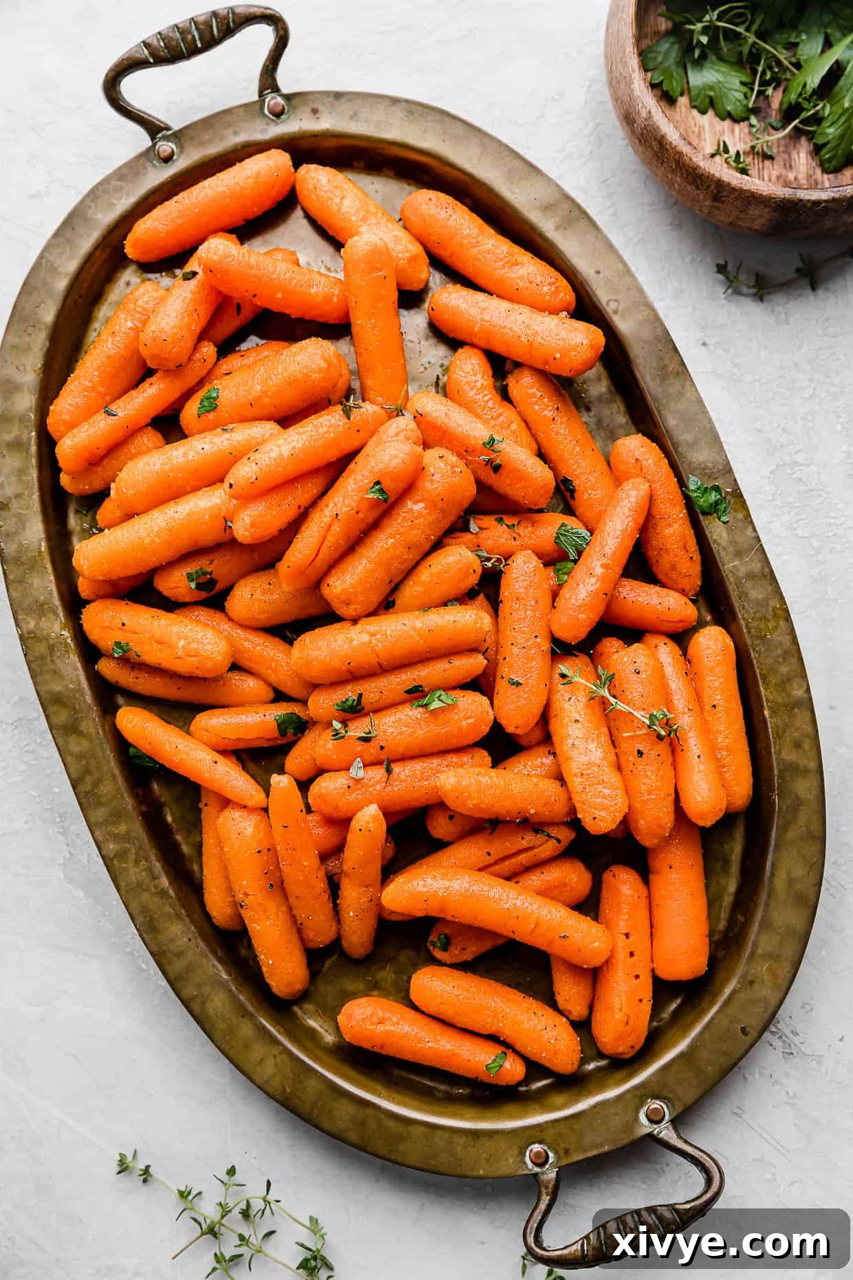 Roasted Baby Carrots on a bronze oval plate on a white background.