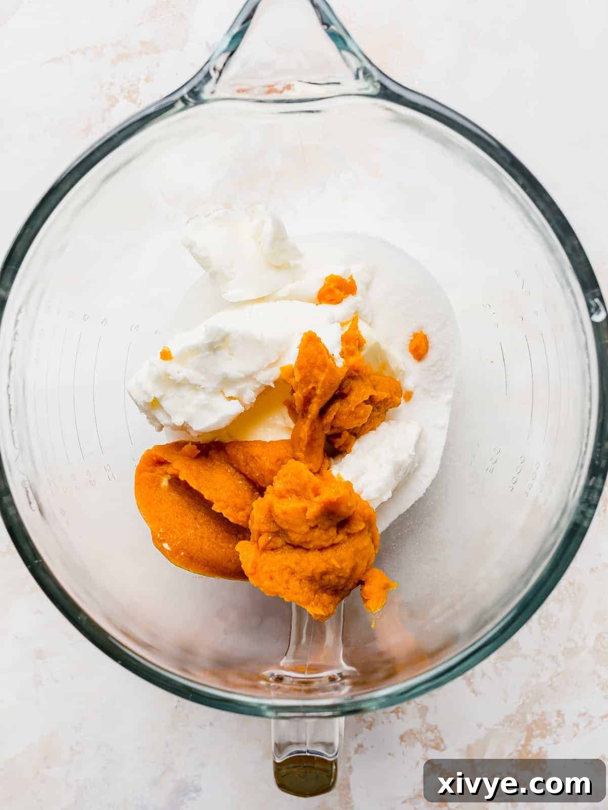 A glass bowl with butter, shortening, and pumpkin puree.