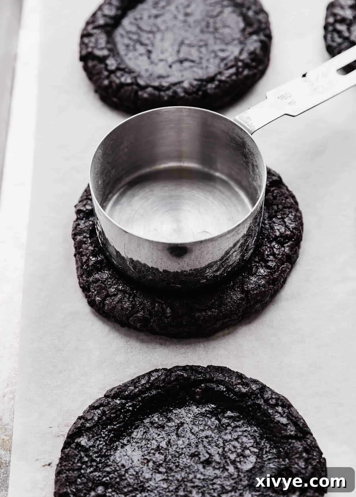 A metal measuring cup pressing into the top of an homemade Oreo cookie, for making a French Silk Pie Cookie.