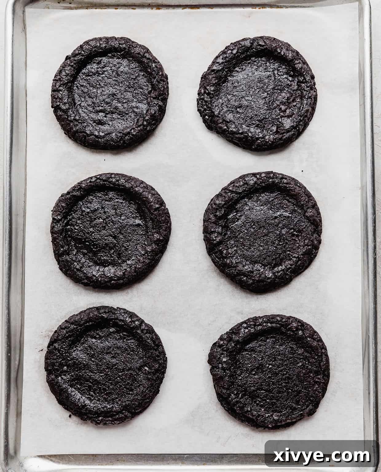 An Oreo cookie based French Silk Pie Cookie on a white parchment paper lined baking sheet.