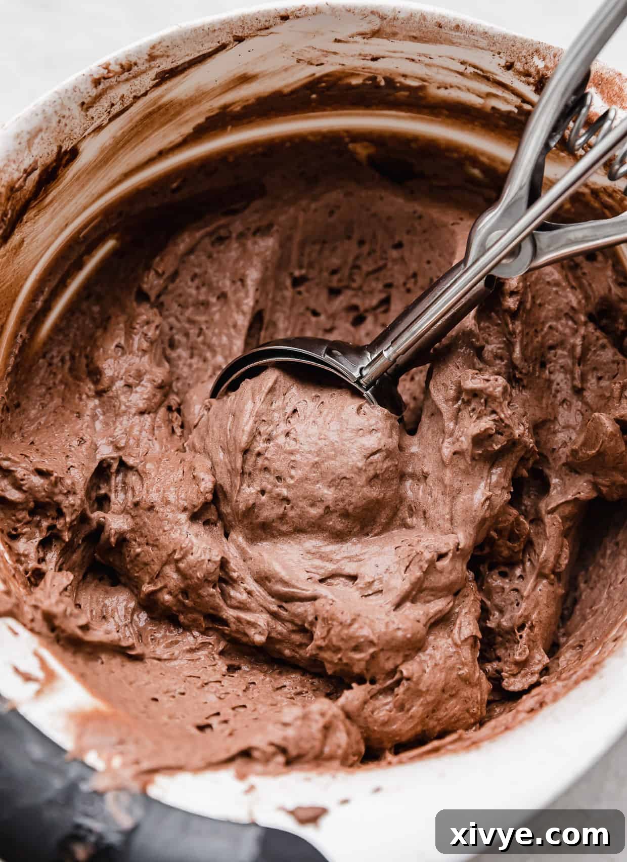 Crumbl homemade chocolate mousse filling used in French Silk Pie Cookies, in a bowl with a cookie scooper scooping out the mousse.