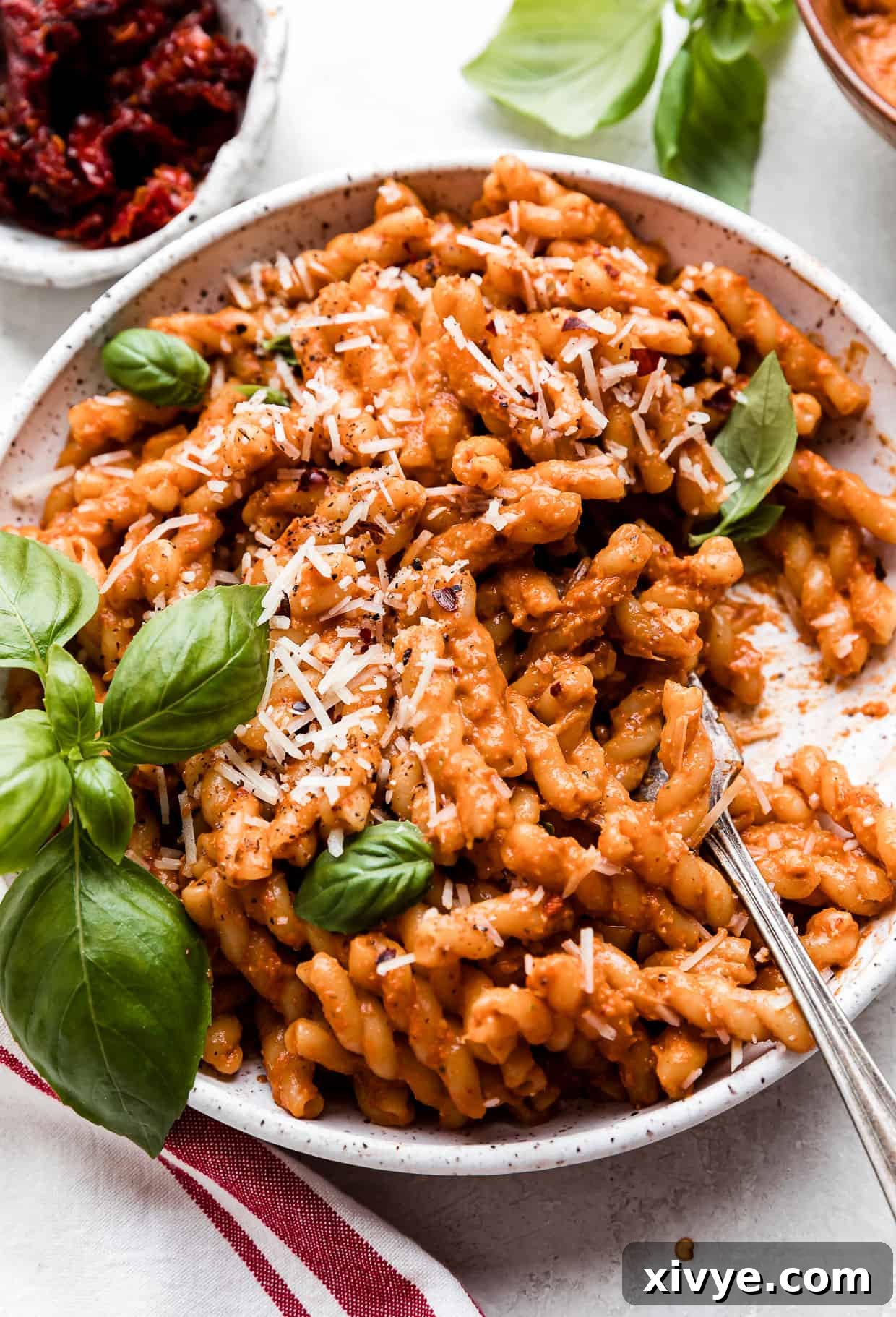 Red Pesto Pasta on a white plate with a fork scooping up noodles.