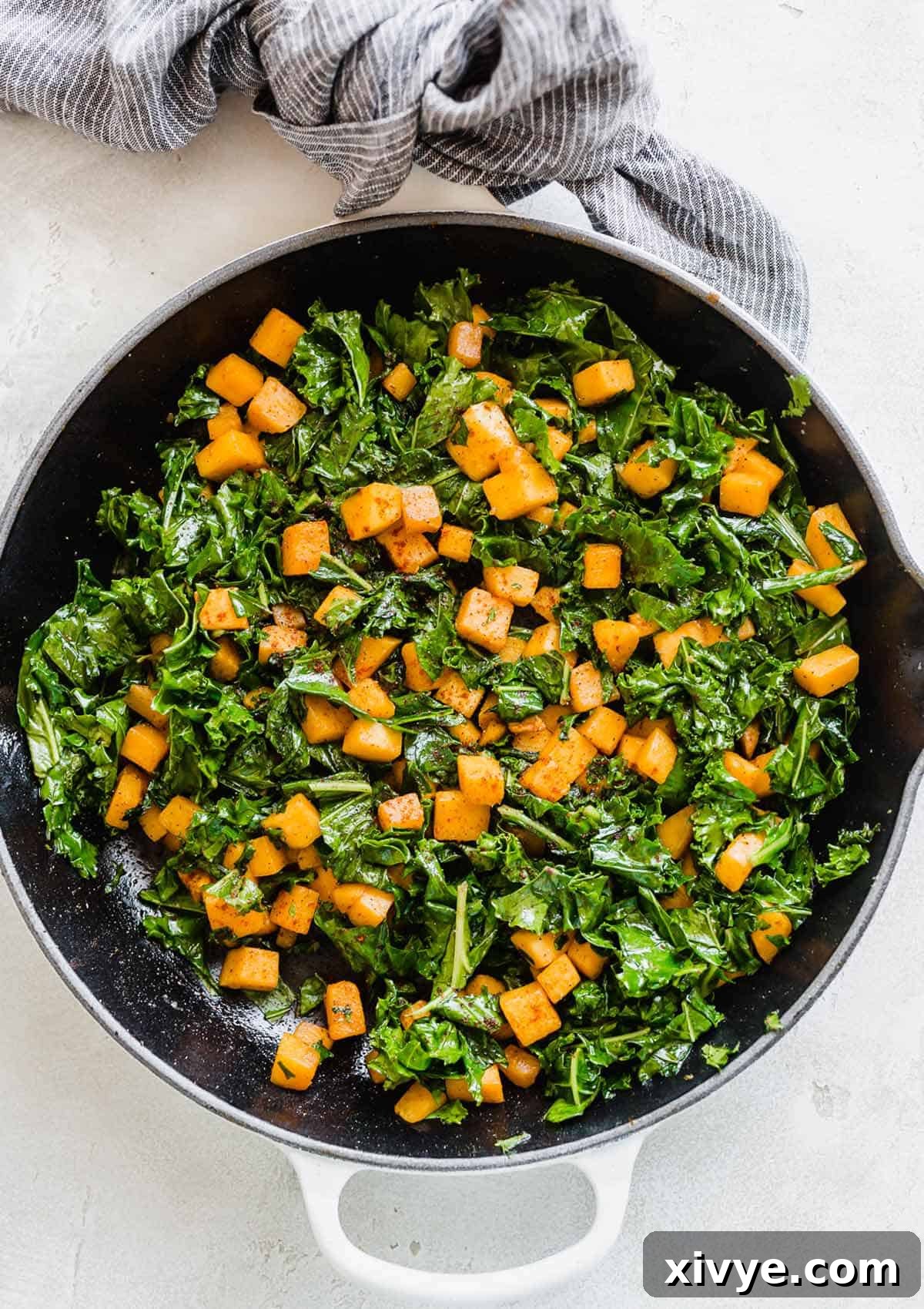 Butternut Squash and Kale Delight 7 Overhead photo of Butternut Squash and Kale in a skillet on a white background, highlighting the vibrant colors and appealing texture.