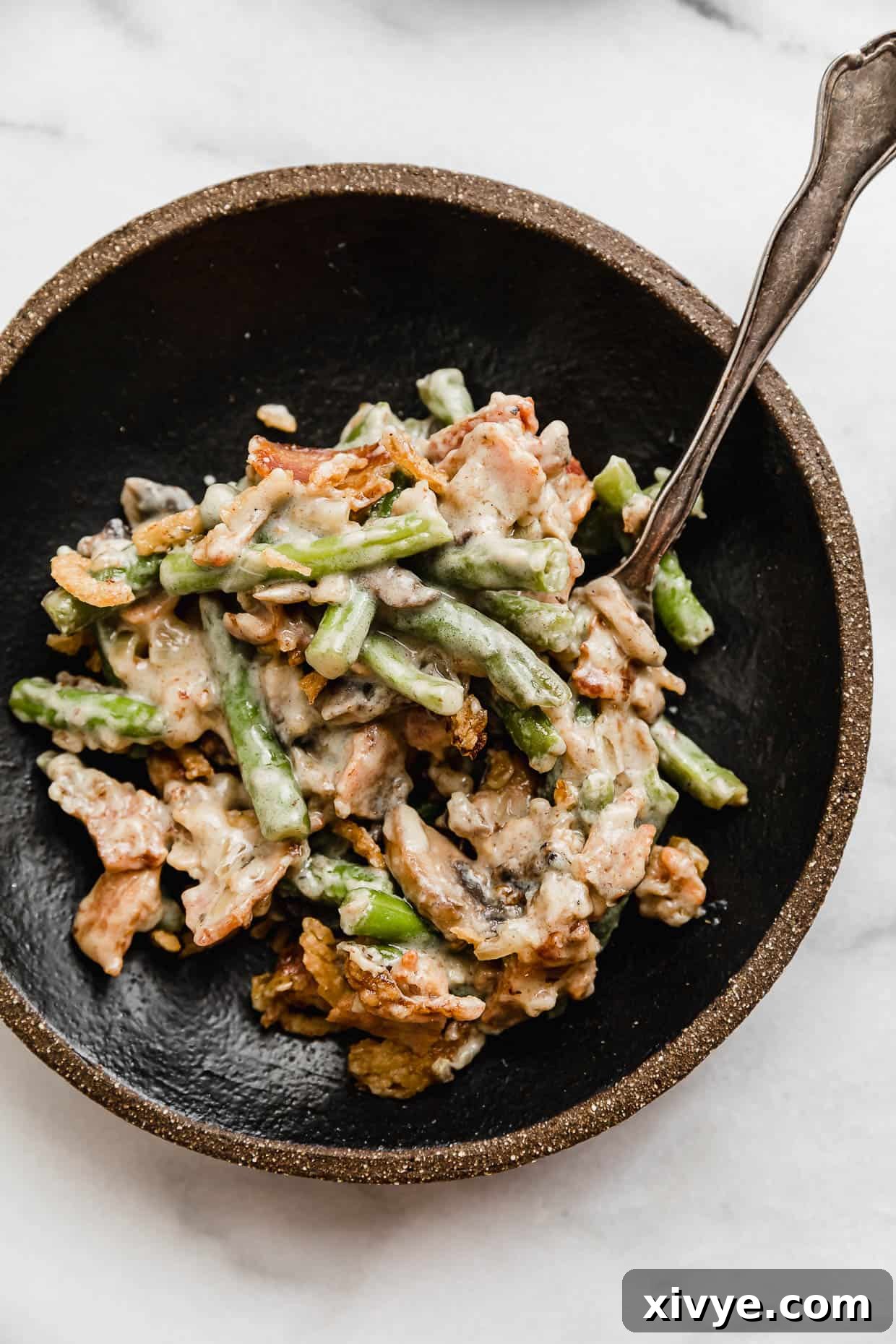 Bacon Green Bean Casserole on a black plate on a white background.
