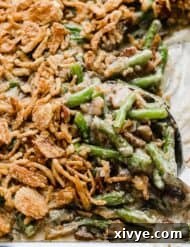 A serving spoon scooping out French fried onion topped Bacon Green Bean Casserole.