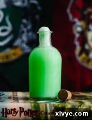 Green Harry Potter Polyjuice Potion in a glass potion bottle in front of a Slytherin and Gryffindor house flag.