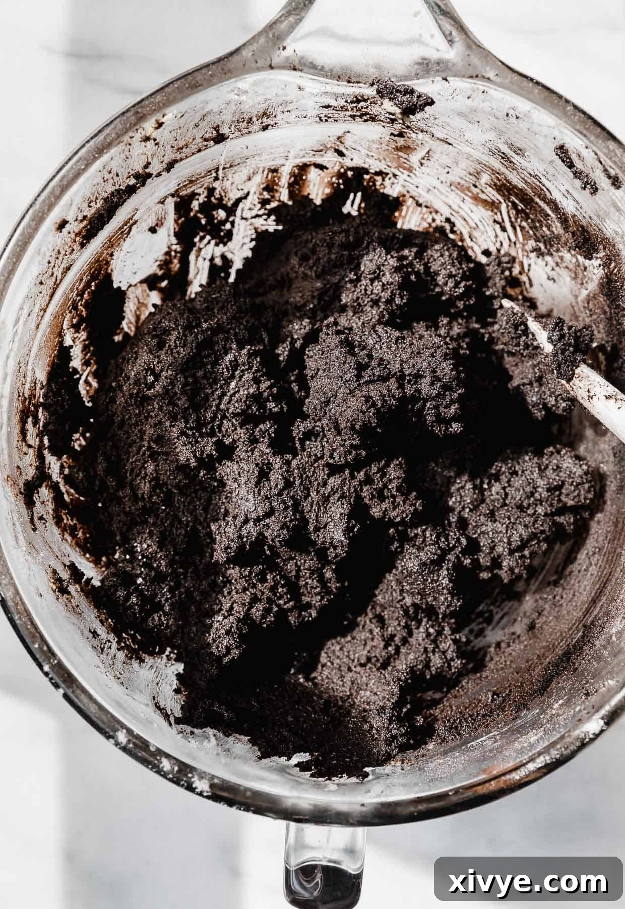 Black oreo cookie dough in a glass mixing bowl.