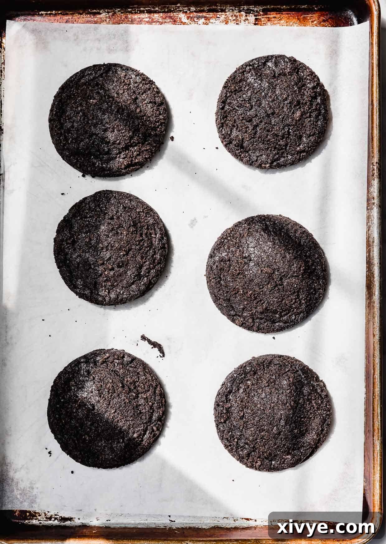 Six baked Dirt Cake Cookies on a parchment lined baking sheet.