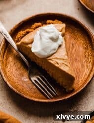 Biscoff Pumpkin Pie topped with whipped cream on a wood plate.