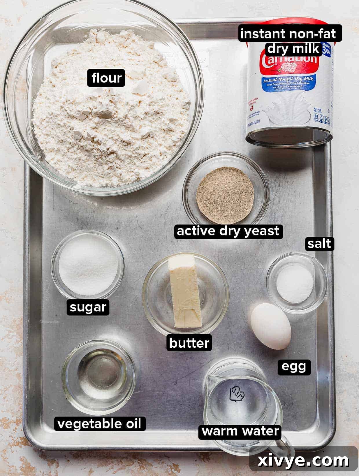 Lion House Rolls ingredients portioned in glass bowls on a silver baking sheet.