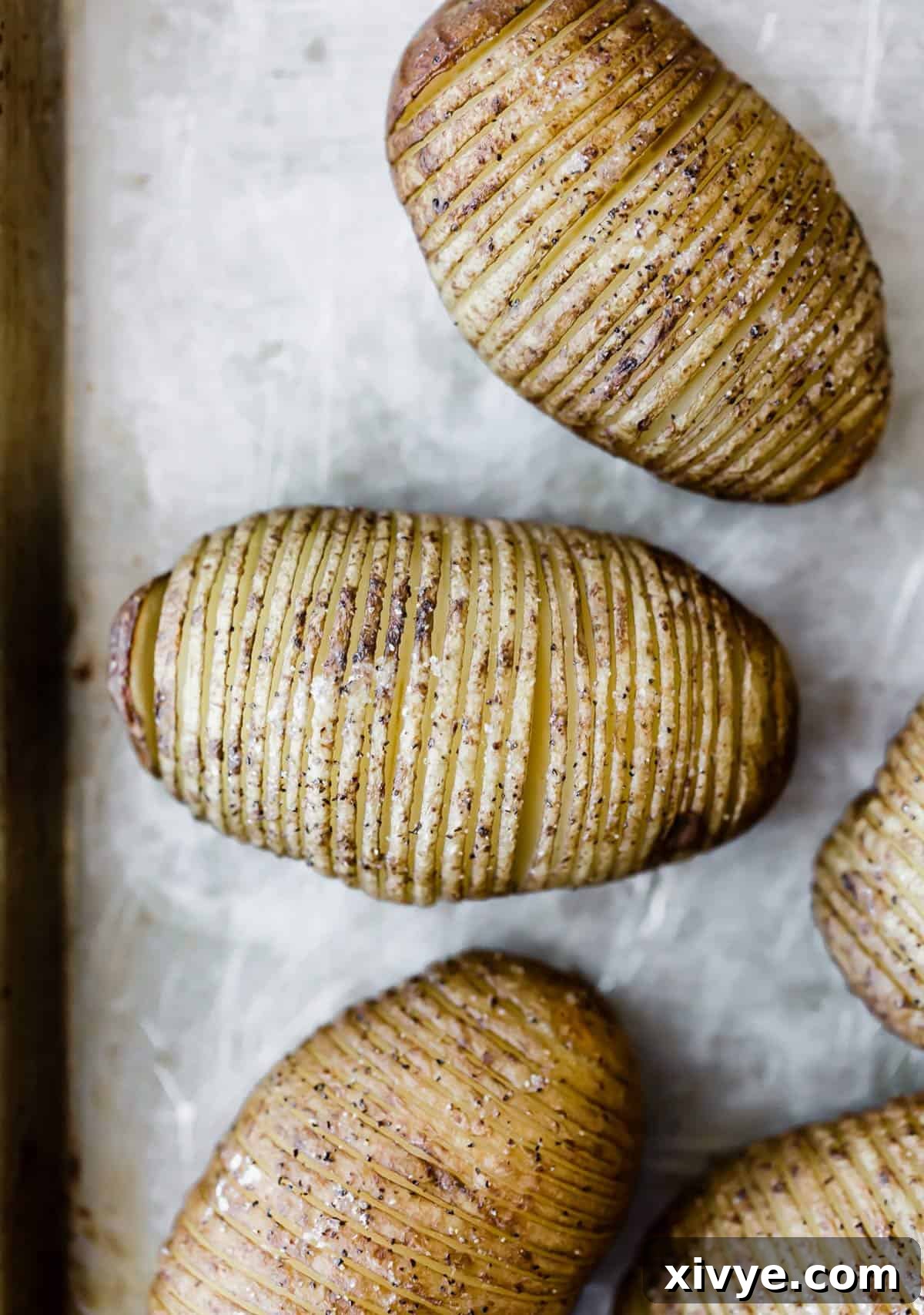 Crispy Air-Fried Hasselback Potatoes 4 Baked crispy Hasselback Potatoes on a gray baking sheet.
