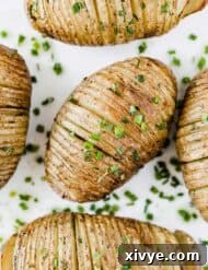 Crispy Air-Fried Hasselback Potatoes 7 Easy Hasselback Potatoes topped with fresh chives on a white background.