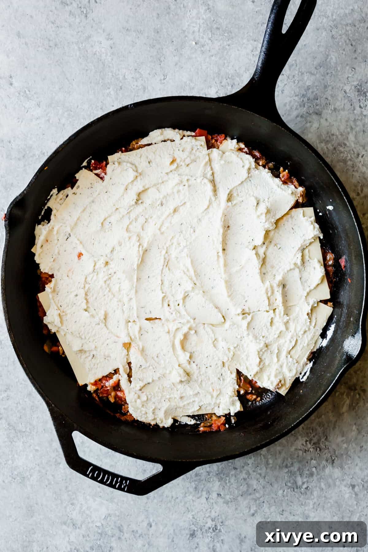Ricotta mixture spread over no-boil noodles, demonstrating a layer within the cast iron skillet lasagna.