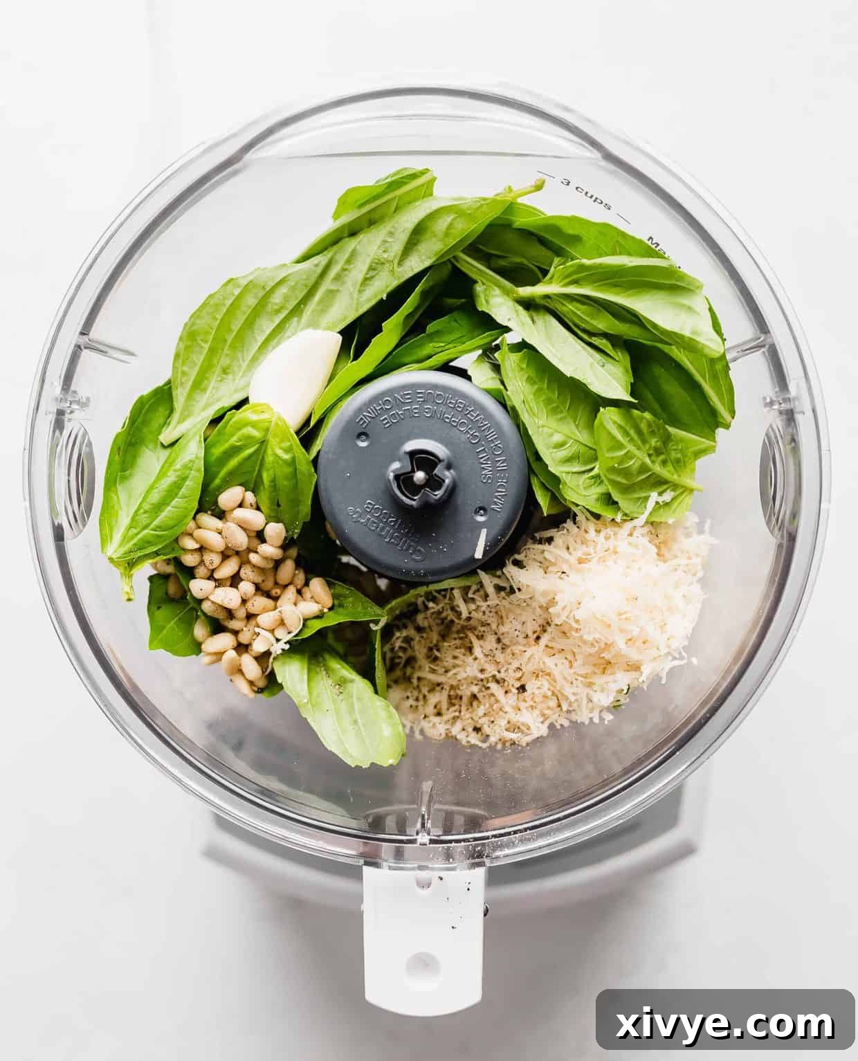 A food processor full of basil pesto ingredients before blending.
