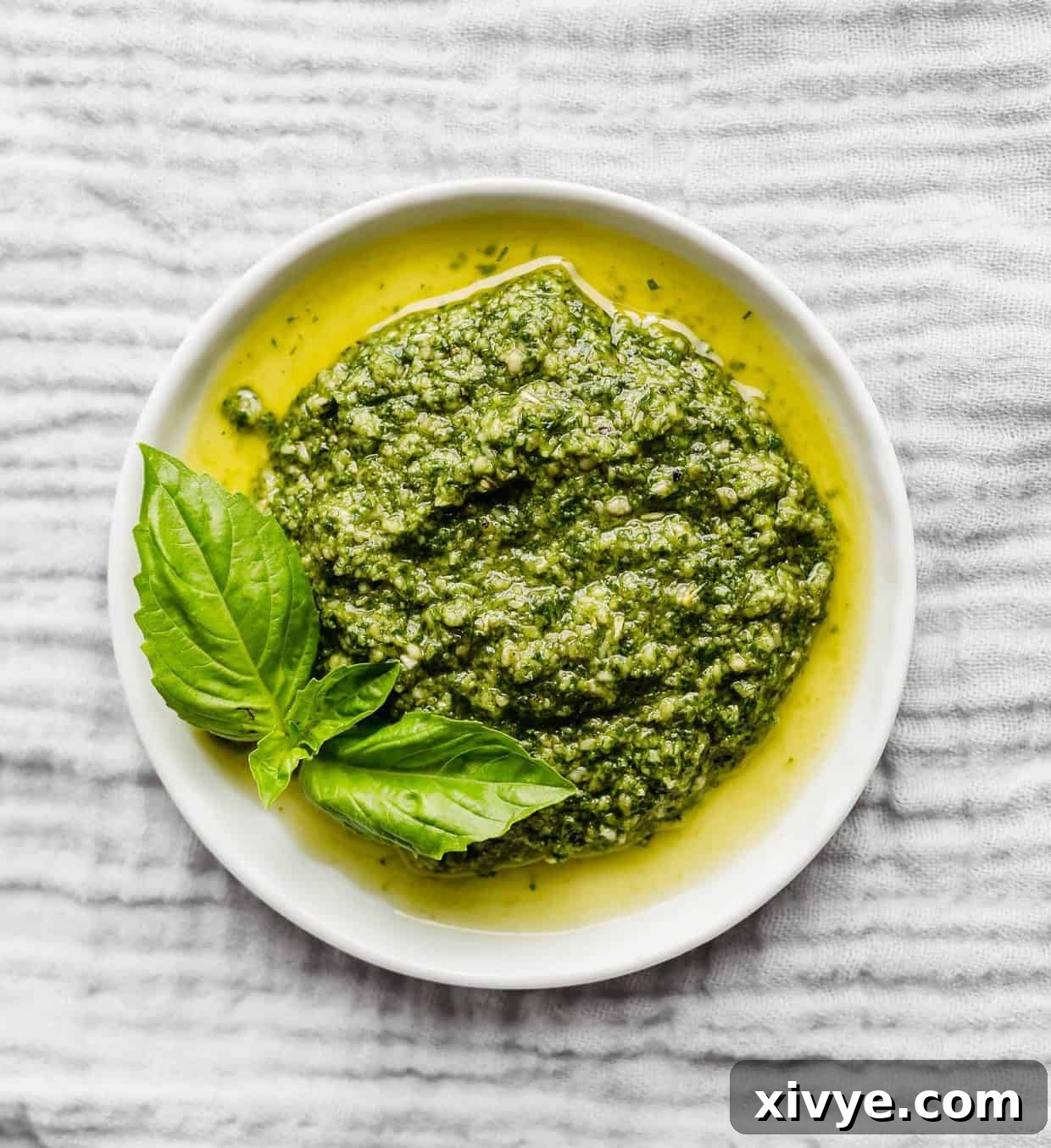 Green pesto on a white plate sitting on a grey napkin, ready to be served or photographed.