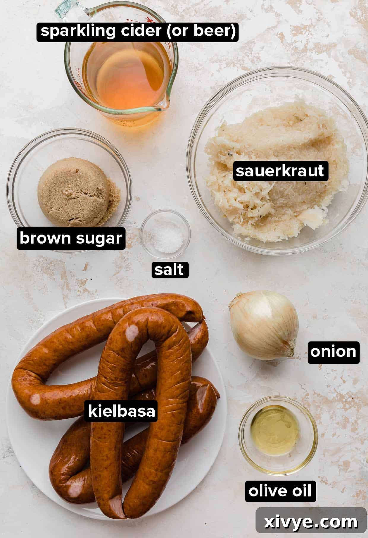 Crock Pot Kielbasa and Sauerkraut ingredients laid out on a white textured background.
