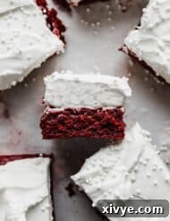 A Red Velvet Brownie square topped with a whipped cream frosting, laying on its side.