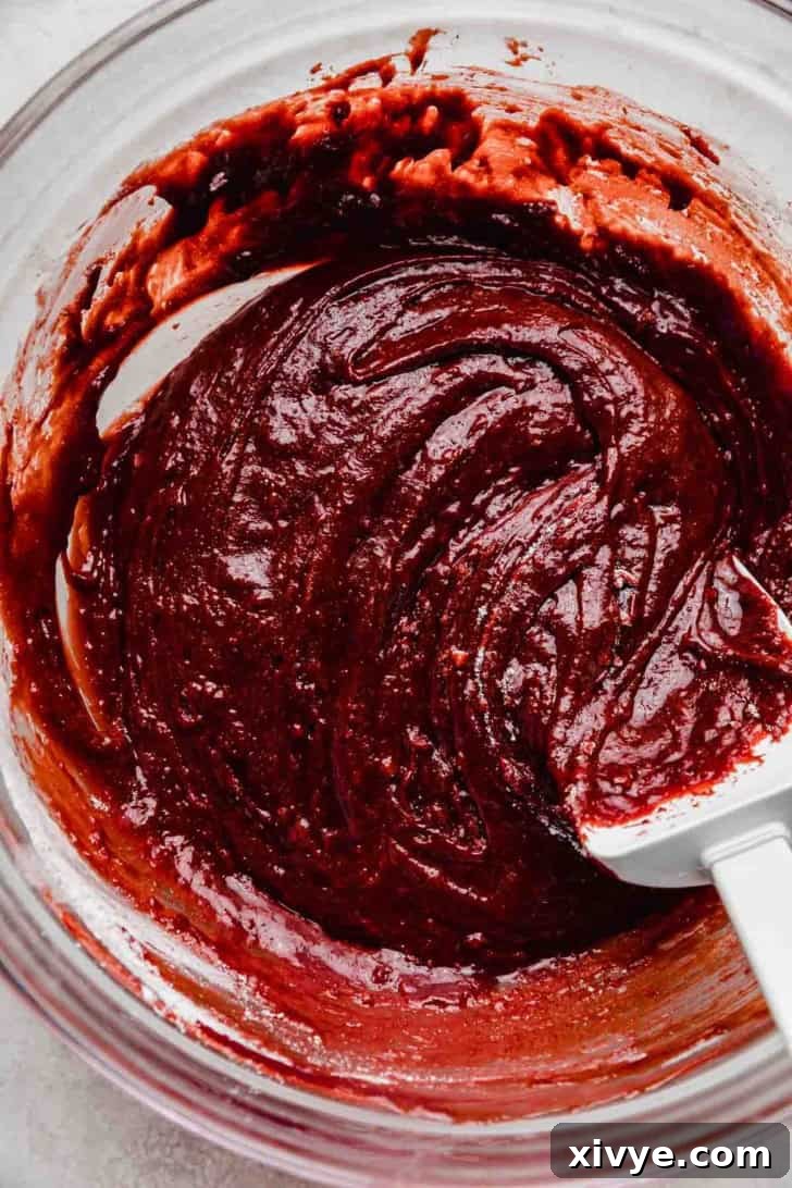 Deep red colored red velvet brownie batter in a glass bowl.