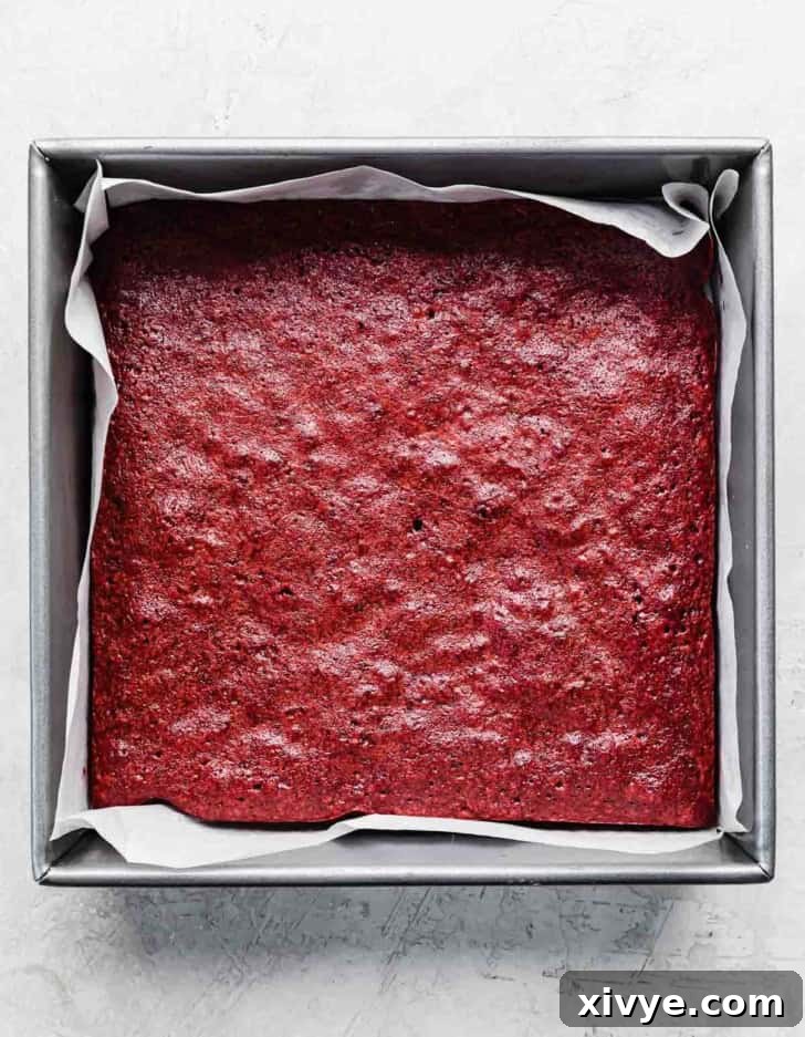 Best red velvet brownies recipe baked in a square pan, on a light gray textured background.