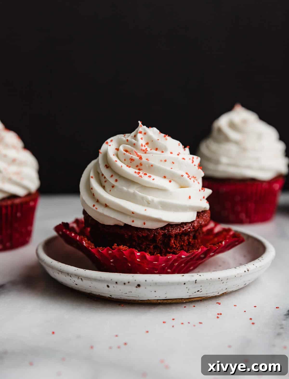 Red Velvet Cupcake on a white plate against a black background.