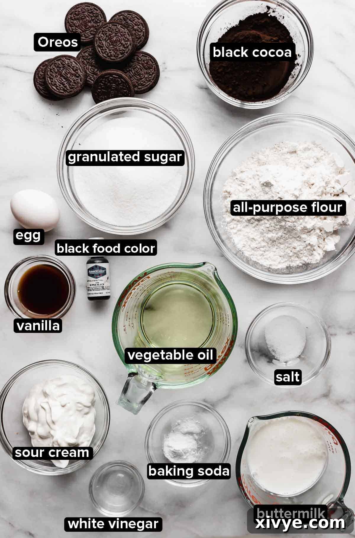 A selection of dry and wet ingredients for Oreo Cupcakes, portioned into clear glass bowls on a bright white background, ready for baking.