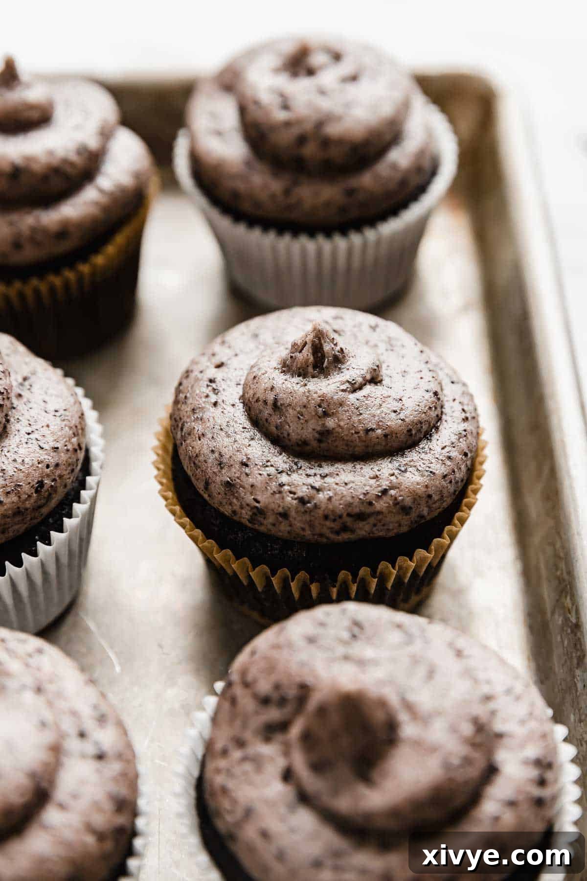 A delicious array of Oreo Cupcakes, each adorned with a perfect swirl of Oreo frosting, neatly arranged on a baking sheet, inviting a sweet indulgence.