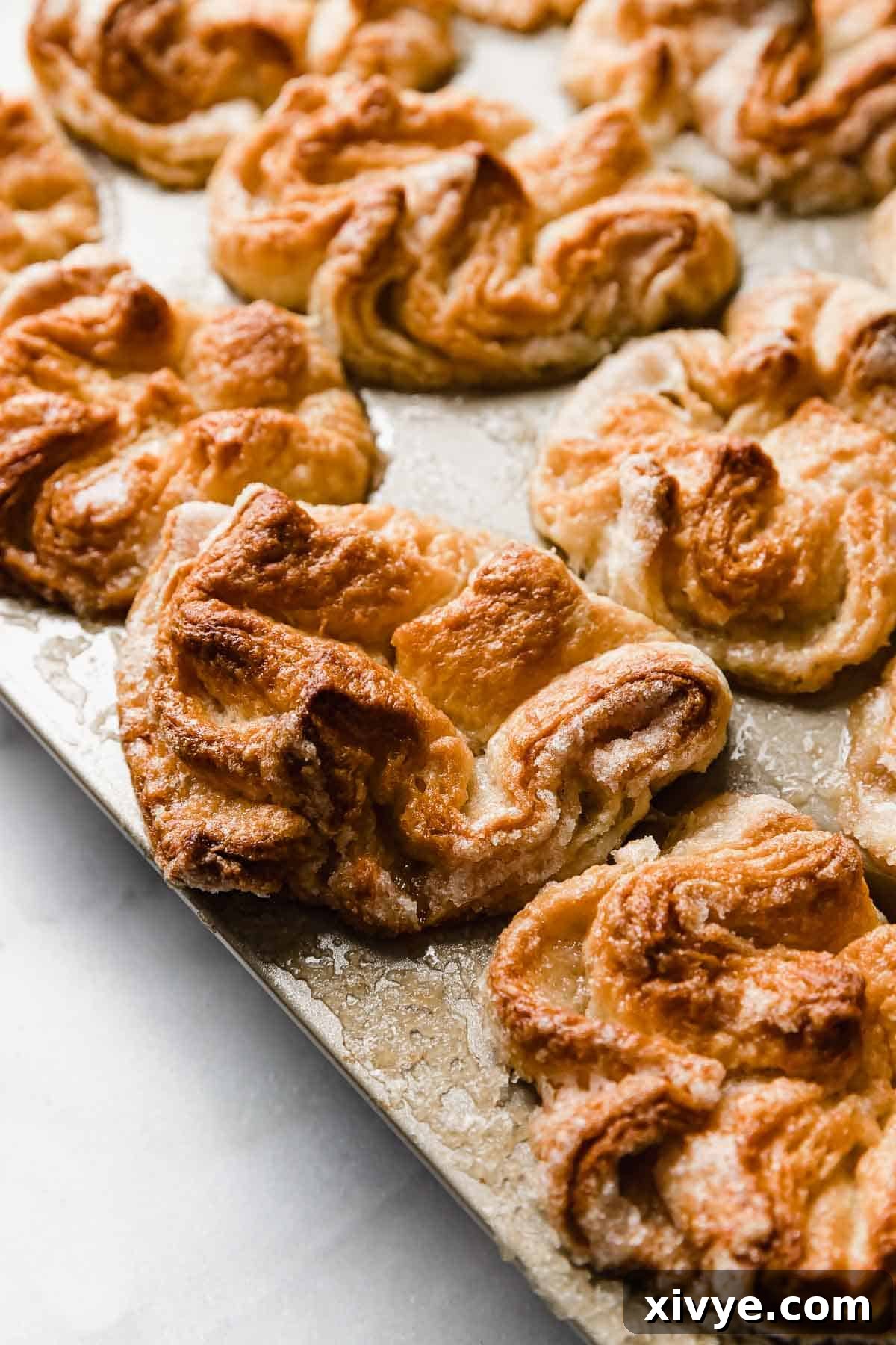 Baked homemade Kouign-Amann in a light gold colored muffin pan.