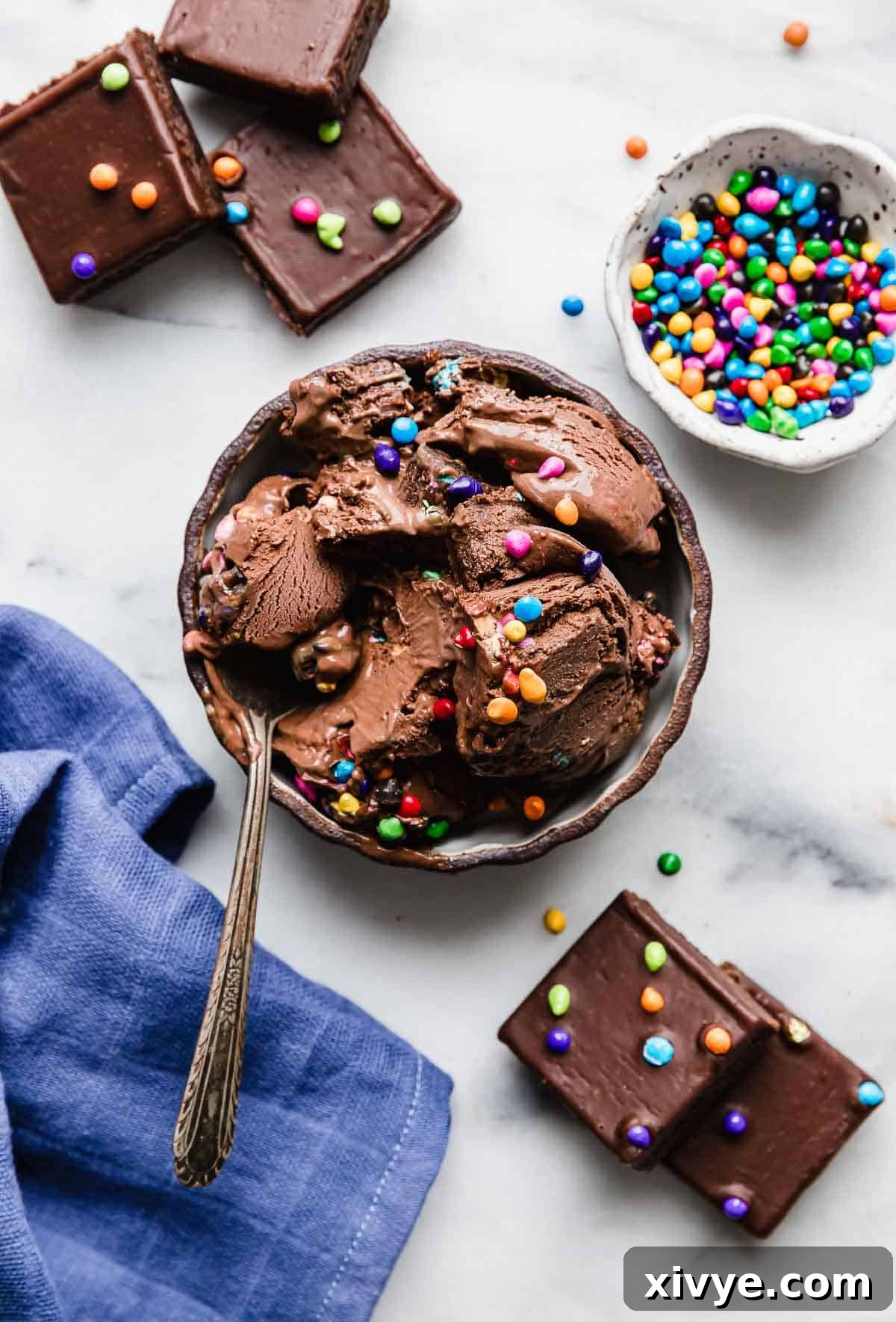Stardust Brownie Galaxy 7 Overhead photo of Cosmic Brownie Ice Cream in a black rimmed bowl on a white background with a small bowl filled with cosmic colorful sprinkles.