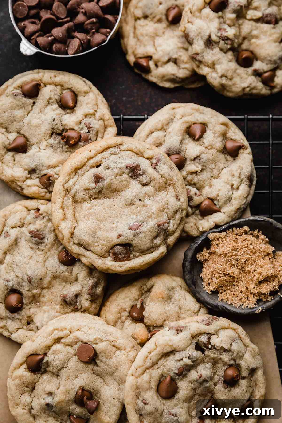 Homemade Milk Chocolate Chip Perfection 2 Freshly baked Milk Chocolate Chip Cookies cooling on a black wire rack, with a small bowl of brown sugar and milk chocolate chips nearby, hinting at the key ingredients.