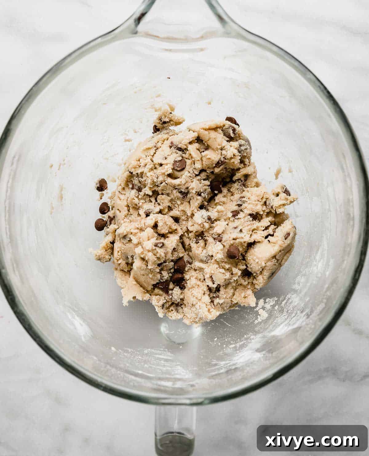 Homemade Milk Chocolate Chip Perfection 4 Smooth and creamy Milk Chocolate Chip Cookie dough ready for baking, resting in a glass bowl within a stand mixer on a clean white background.