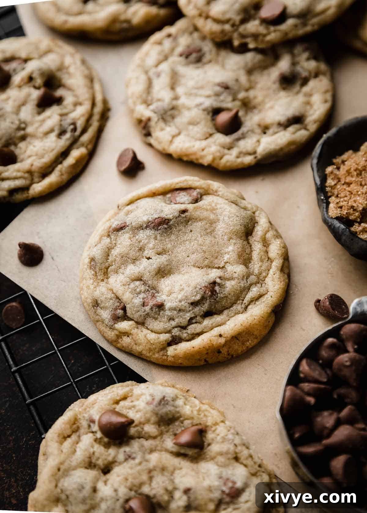 Homemade Milk Chocolate Chip Perfection 7 The best Milk Chocolate Chip Cookies beautifully arranged on Kraft colored parchment paper, surrounded by a generous scattering of milk chocolate chips.
