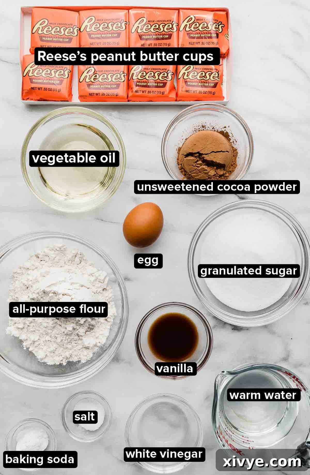 Reeses peanut butter Cupcake ingredients portioned into glass bowls on a white marble background.