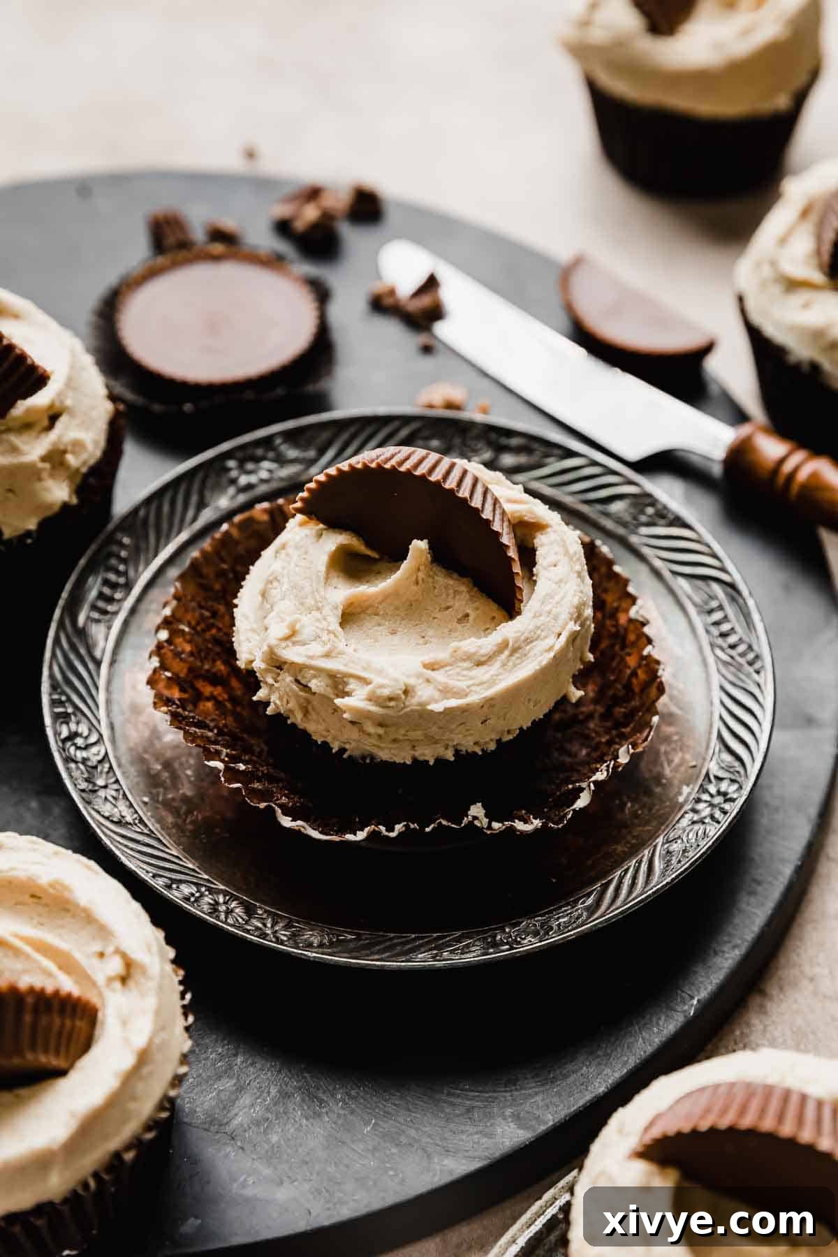 A Reeses Cupcake topped with peanut butter frosting and half of a Reese's peanut butter cup.