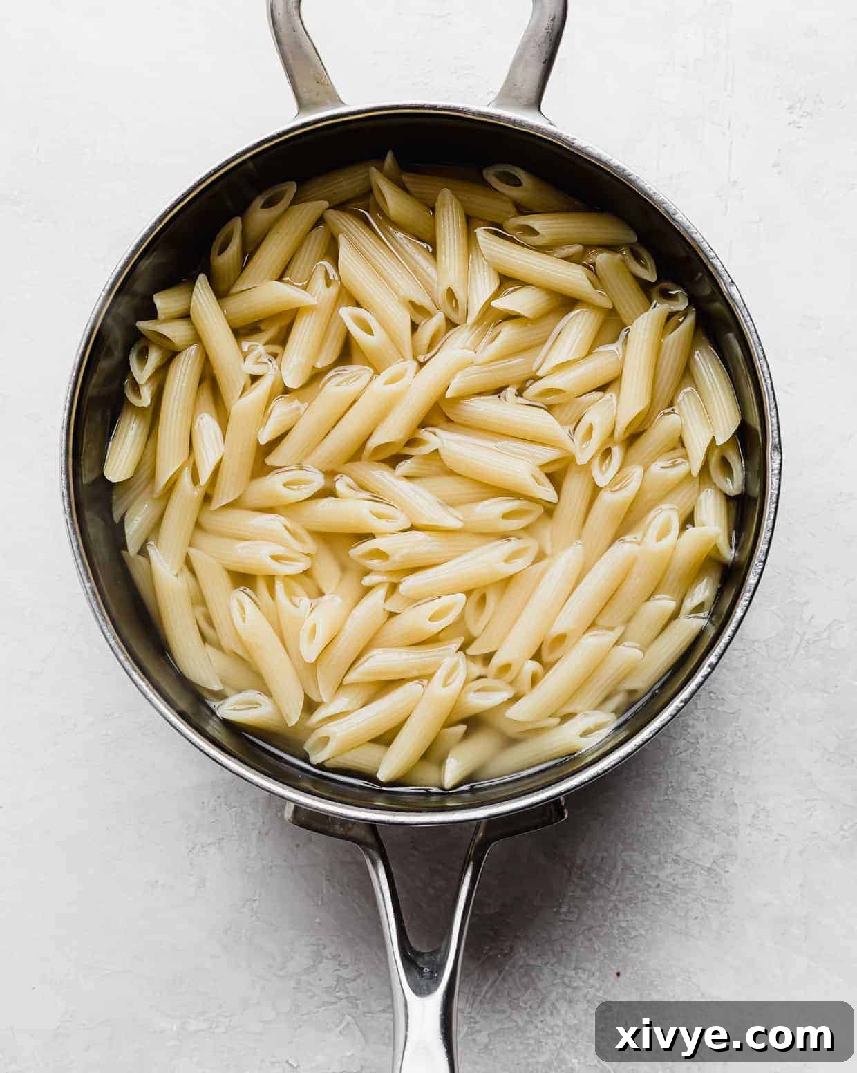 A saucepan with penne noodles in it. 